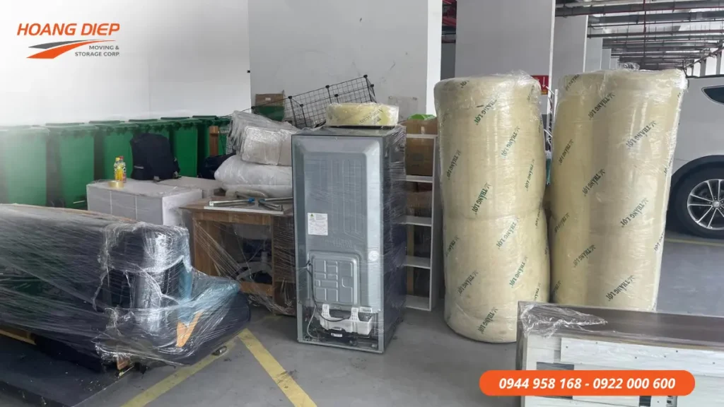 Hình ảnh đồ nội thất, nệm và thiết bị gia dụng được bọc màng bảo vệ, tập kết trước khi vận chuyển trong quá trình chuyển nhà chung cư.